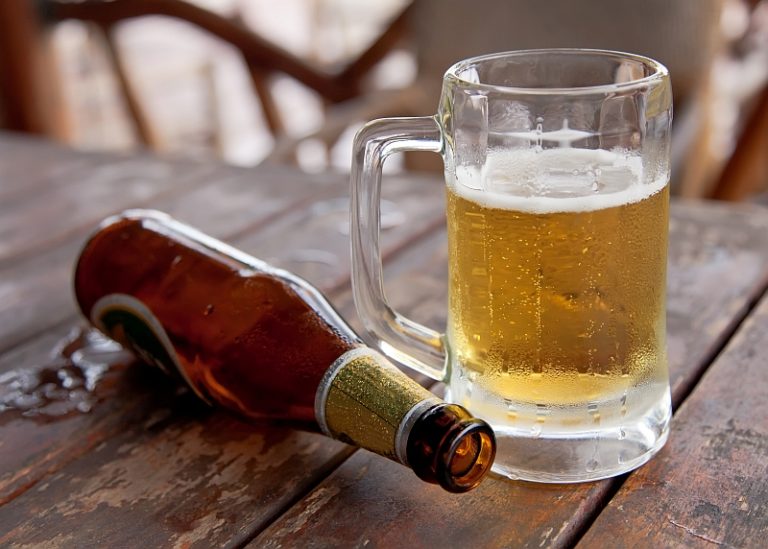 Open beer bottle and glass of beer showing how alcohol affects sleep quality and causes fatigue