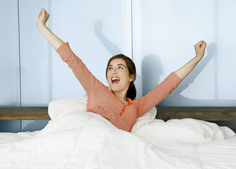 Woman waking up refreshed and energized after improving sleep through Cognitive Behavioral Therapy (CBT) and healthy sleep habits.