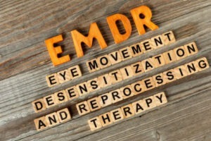 Wooden letter tiles spelling EMDR eye movement desensitization and reprocessing therapy for trauma treatment.