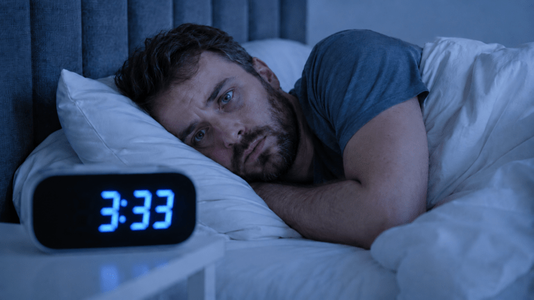 A tired adult awake in bed wondering why they wake up at 3 A.M. every night